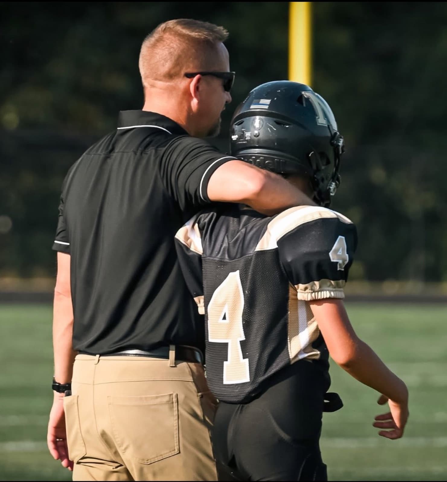 Kyle Frick on the sideline with his arm around one of his football players